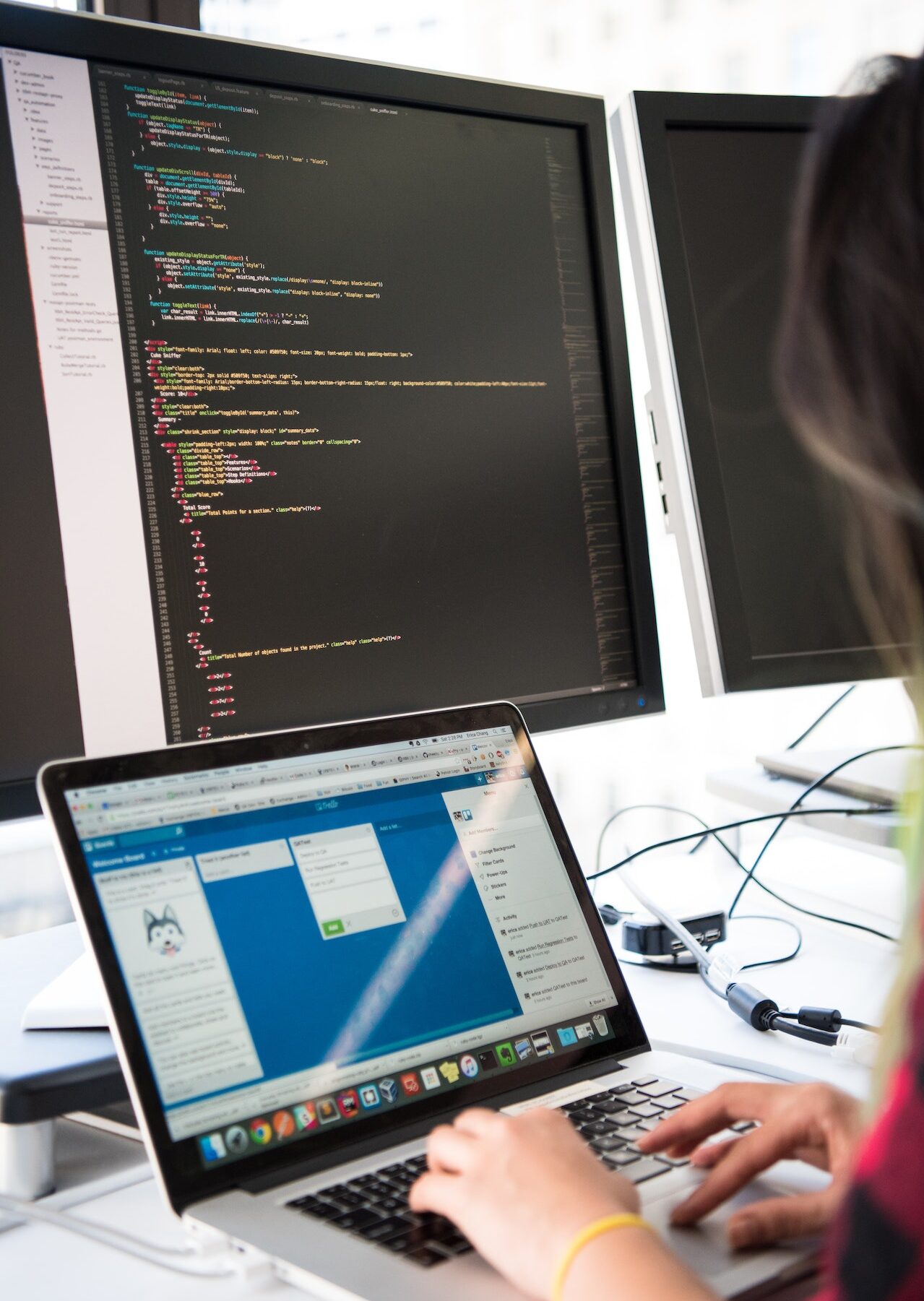 Woman at desk in front of multiple computer screens of computer code | Network Monitoring